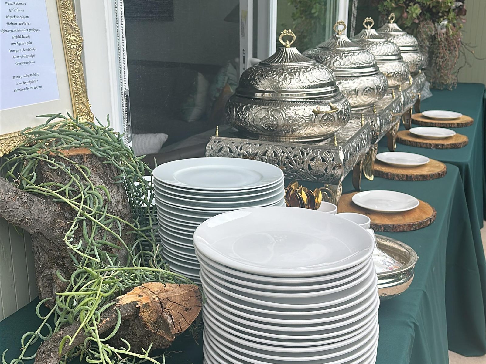 Plates and engraved chafing dishes ready for service at an outdoor event